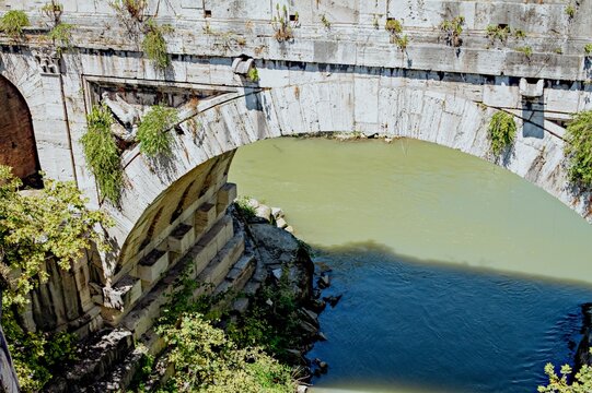 Ancient stone bridge arch over a river with distinct water colors