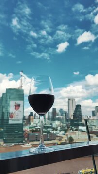 red wine on terrace with Bangkok city skyline at sunset, cocktail on rooftop, vibrant cityscape and luxury panorama view 4k