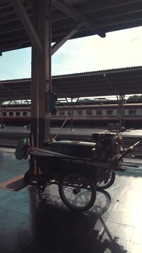 cleaning cart with hose and bucket at railway station, mobile trolley for platform sanitation, daily rail service and maintenance routine, 4k vertical video