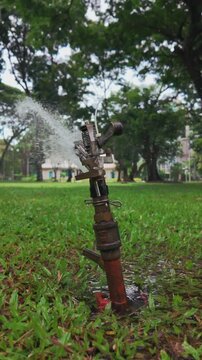 closeup of sprinkler watering lush lawn in vibrant garden, close-up of irrigation system hydrating green turf with refreshing water spray, 4k vertical video