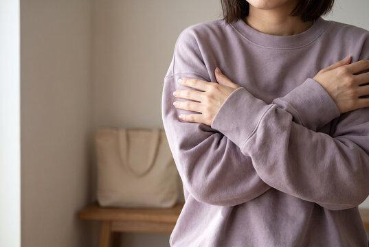 両腕を抱えて寒さをこらえる女性の上半身