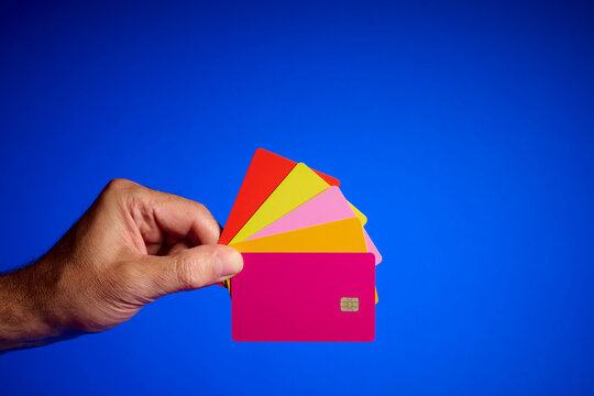 Close-up of a man hand holding several credit cards of different colors.