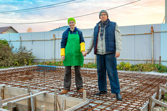 Two people holding hands on a rebar foundation at a home construction site. Couple building a house together. Family teamwork and partnership. Residential construction and home building