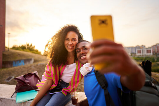 Young diverse couple taking selfie during sunset