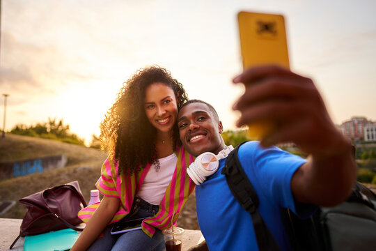 Young smiling diverse couple taking selfie during sunset