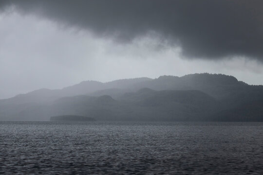 Fog covering mountains behind a lake near Soldotna, Alaska on a dark summer day.