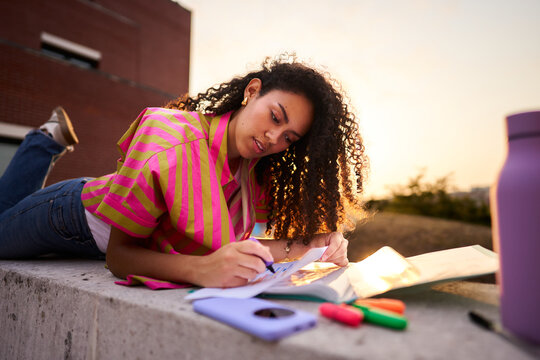 Young woman studying outdoors at golden hour