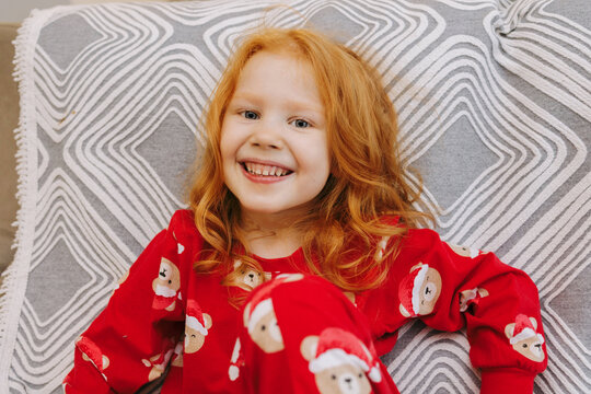 The girl is smiling as she sits on the sofa.