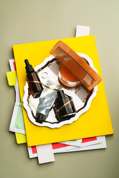 Stack of cosmetics and accessories in silver plate over pile of papers