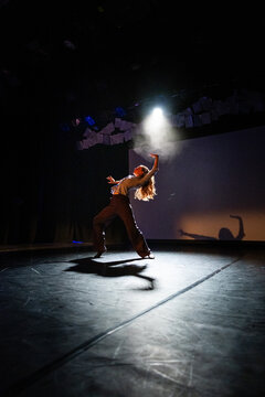 A dancer spins dramatically beneath a single spotlight