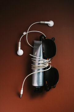Sunglasses and metal cream tube tied together with wired earphones