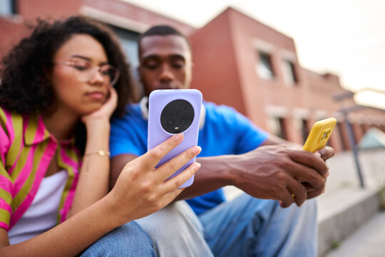 Young couple ignoring each other using smartphones outdoors