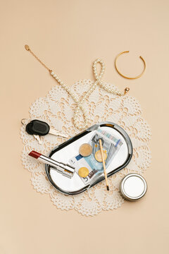 Jewelry and makeup with money in silver plate on crochet tablecloth