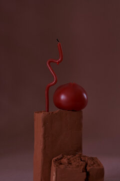 An abstract composition with candle, clay and an apple