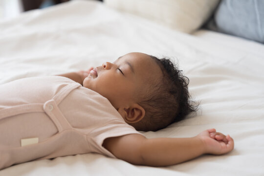 African American newborn little black baby boy taking sweet peaceful nap on soft white blanket, healthy sleep concept for innocent newborn child at home