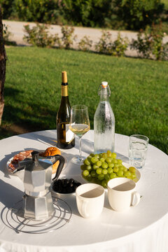 Moka pot and grapes catch the sun on an open terrace