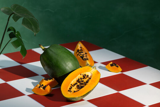 Fresh halved papaya fruit and and lush monstera leaves