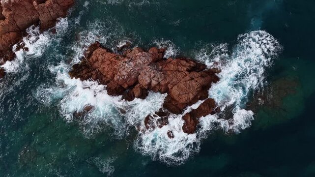 Red rock islets surrounded by white foam Costa Brava Spain
