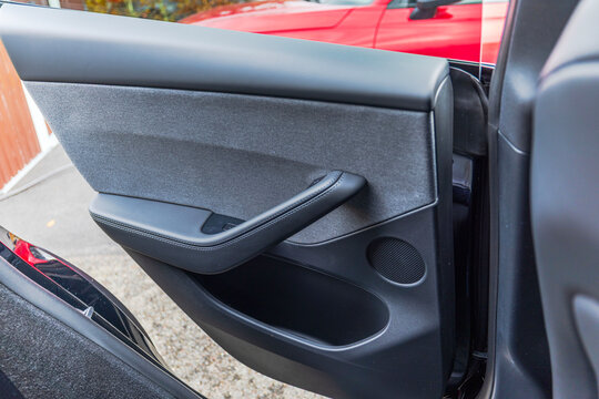 Close-up view of open car door with fabric upholstery, stitched armrest, speaker and storage pocket. Sweden.