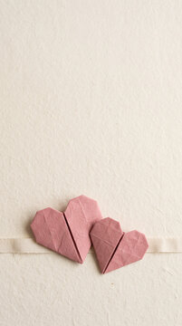 Pink paper hearts and ribbon on a cream background