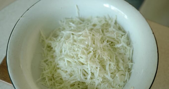 Close-up male hands stir cabbage in metal bowl. 4K 10-bit