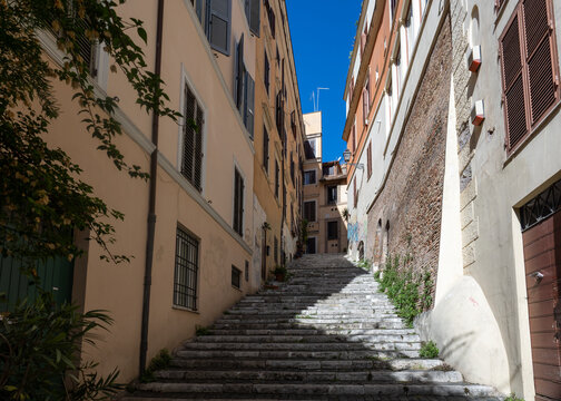 Narrow stone staircase between old pastel buildings in a quiet alley in the historic centre of Rome, Italy