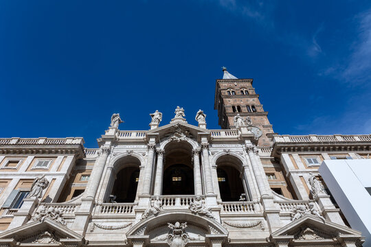 Facade of Santa Maria Maggiore basilica with statues and bell tower against deep blue sky, Rome, Italy