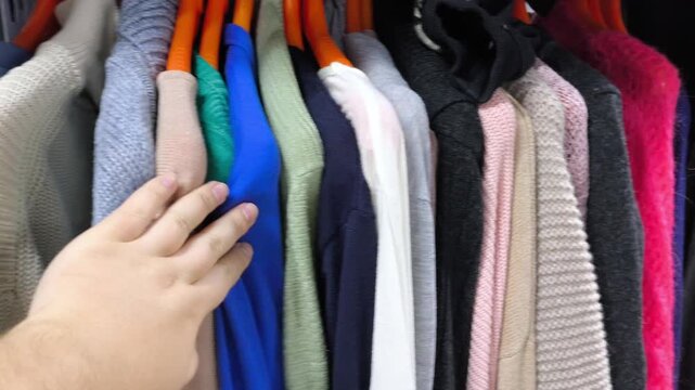 Women's hands choosing clothes from a hanger. Shopping at a second-hand store. Caring about the environment.