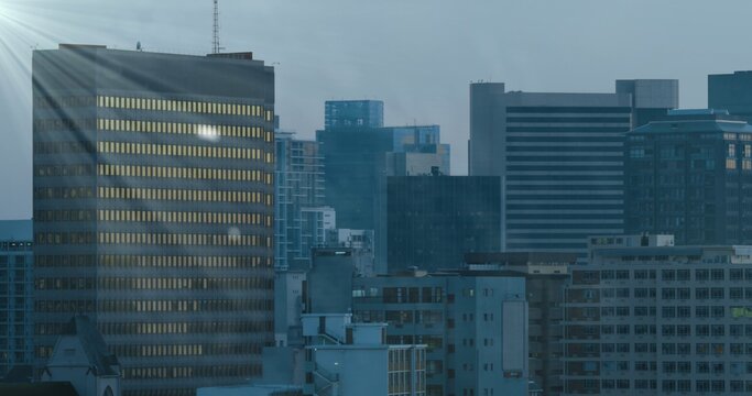 Casting rectangular office tower showing lit window rows glowing warm at downtown dusk, copy space