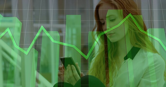 Holding smartphone, woman in light blouse with dark collar viewing green charts office, copy space