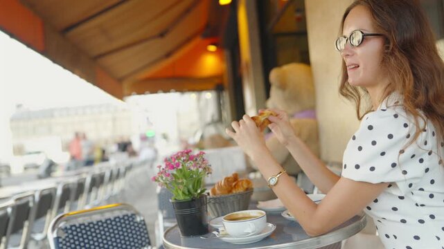 Woman in sunglasses enjoying croissant and coffee at Paris cafe