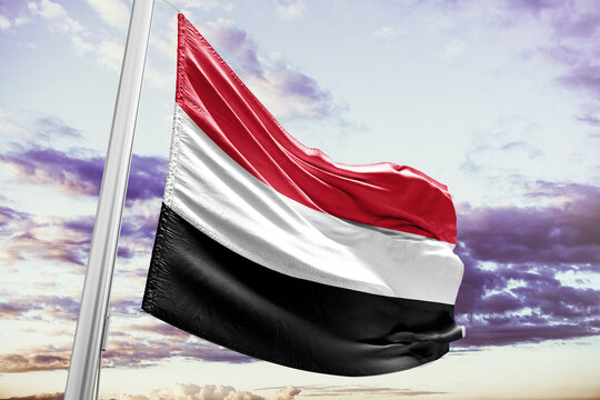National Flag of Yemen Waving on Flagpole against Cloudy Sky