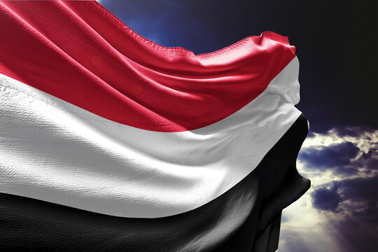 Waving flag of Yemen against a dramatic cloudy sky