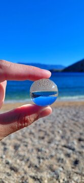 Creative lensball view of Baska beach on Krk island, Croatia. Crystal-clear turquoise Adriatic Sea inverted in a glass sphere. Sunny summer landscape of Kvarner bay. Artistic travel photography.