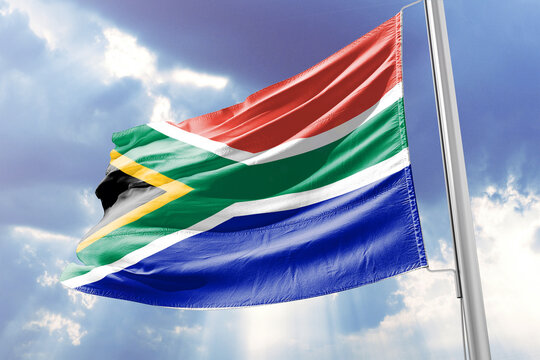 South African flag waving against a blue sky with clouds