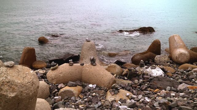 Ocean waves splashing gently against rocky beach and concrete tetrapods