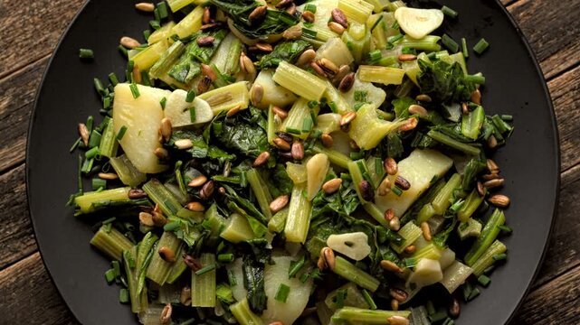 Cinematic flat lay of a rotating traditional Croatian blitva s krumpirom chard dish with toasted sunflower seeds.