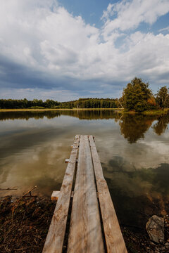 Wooden jetty and pond with dramatic clouds