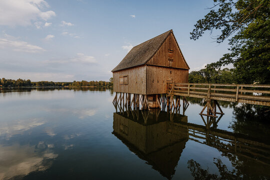 Wooden stilt hut reflected in pond