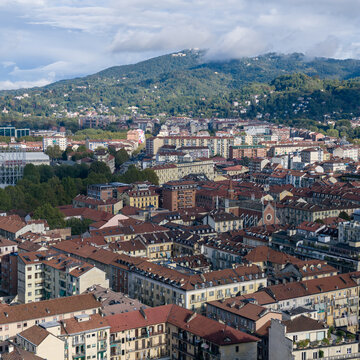Turin cityscape, stretching across red tiled rooftops toward cloud covered wooded hills