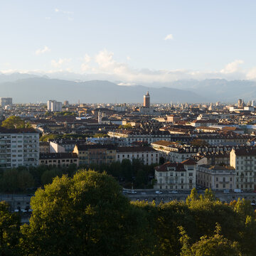Turin's historic rooftops and urban skyline glowing in evening light beneath the Alps