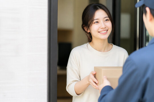 玄関で配達員から荷物を受け取る日本人女性