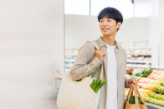 スーパーで野菜入りのエコバッグを持つ日本人男性