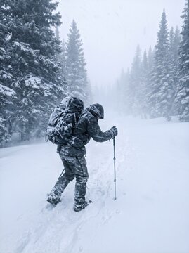 Hiker walking through a blizzard in a snow-covered forest  