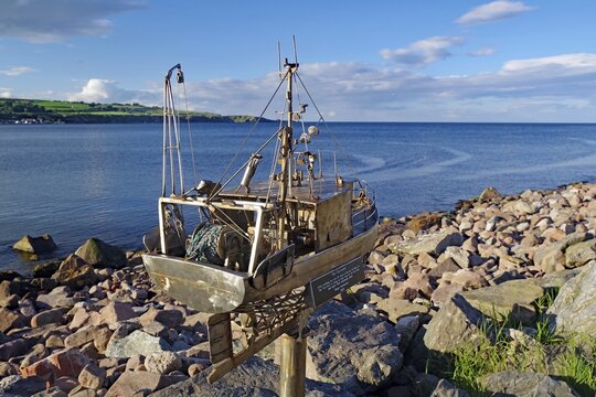 Model of a metal fishing boat, on a rocky coast under a blue sky, art, Stonehaven, Scotland, Great Britain
