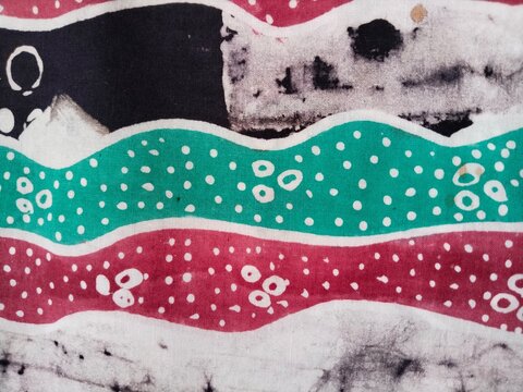 Traditional Indonesian batik fabric pattern with red green and white colors, Javanese textile texture