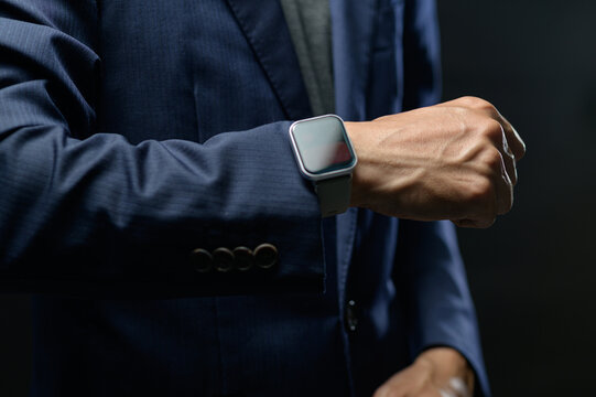 Man in formal suit checking smartwatch on wrist in professional setting