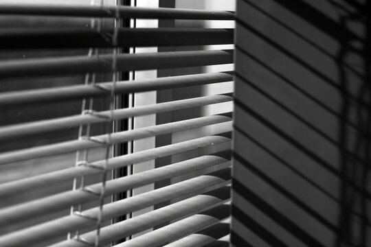 Light from the window passes through a sun-blocking curtain, creating shadows on the concrete wall.