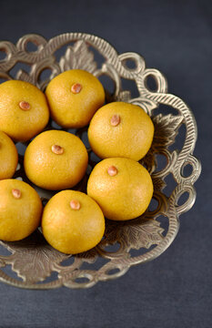 Close up top view of delicious home made Besan Laddus arranged on an ornate bowl. Rich golden hue, smooth round shape dessert evoking Diwali celebration and tradtion.