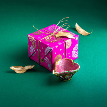 An elegant gift box wrapped in a bright paper placed with Diwali lamp. An Indian festive gifts or a Diwali greeting card photo.        